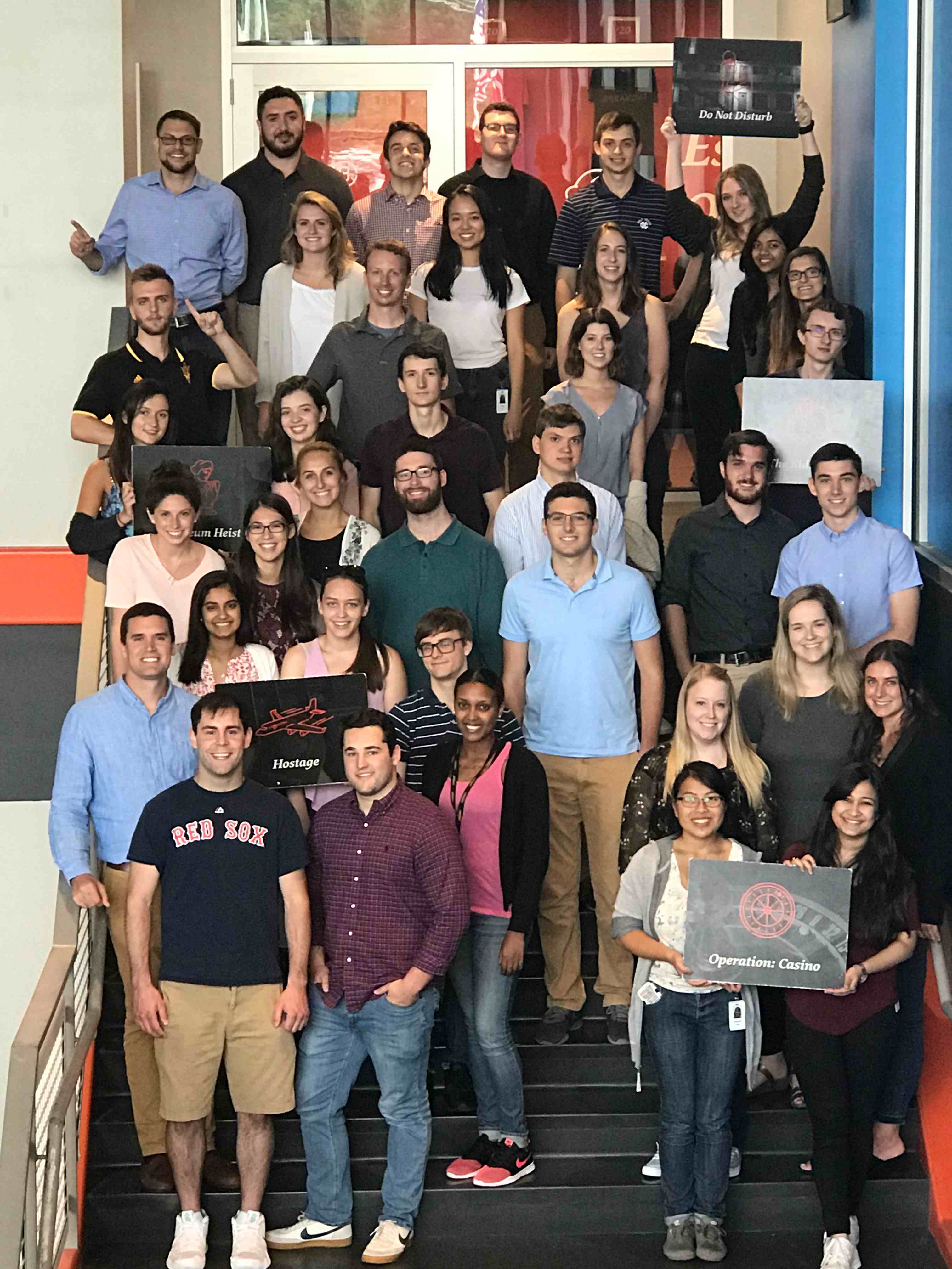 Group of students standing on stairs holding signs 